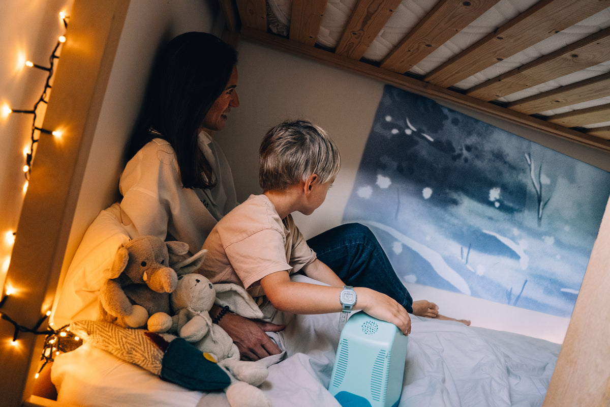 Une maman et son fils regardent ensemble une histoire Tikino projetée au mur