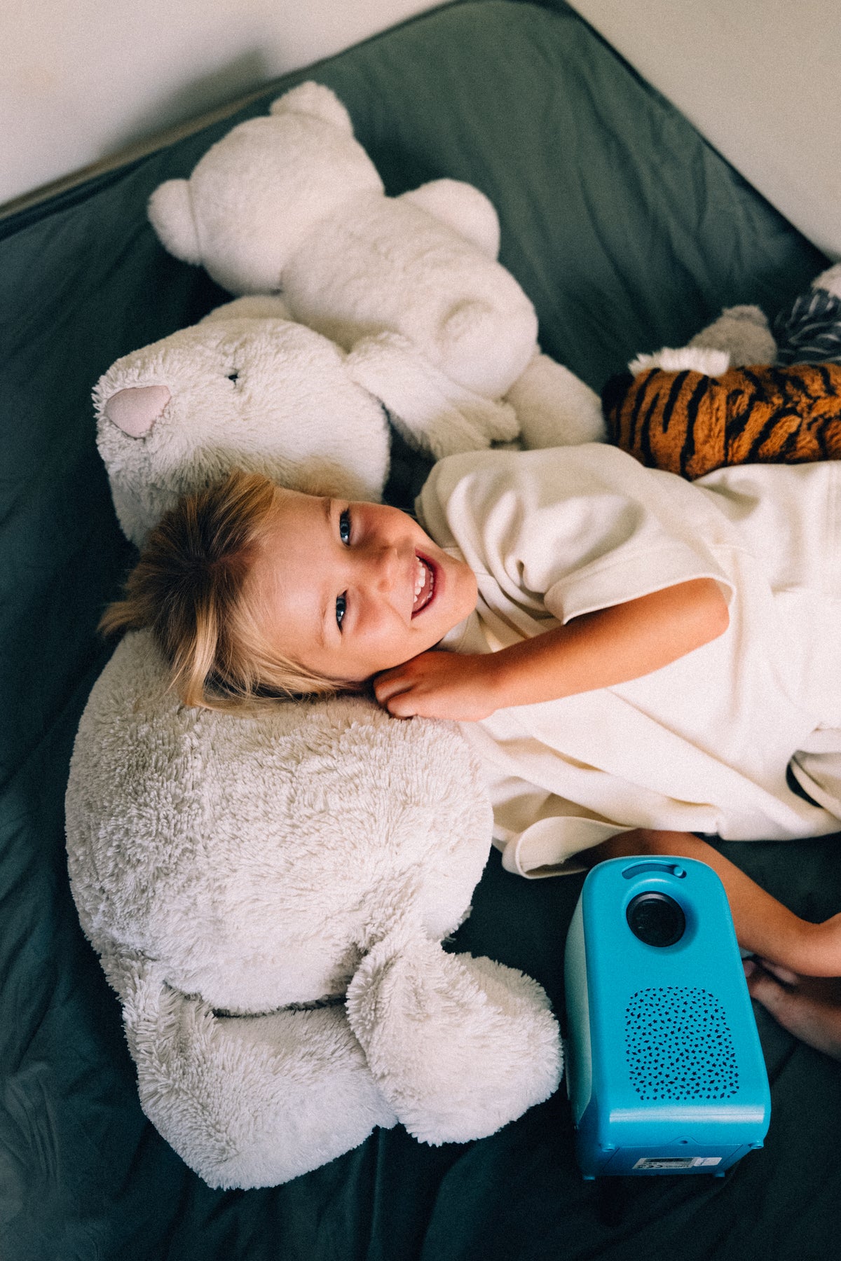 Une petite fille installée sur des coussins, le projecteur Tikino posé à côté d'elle